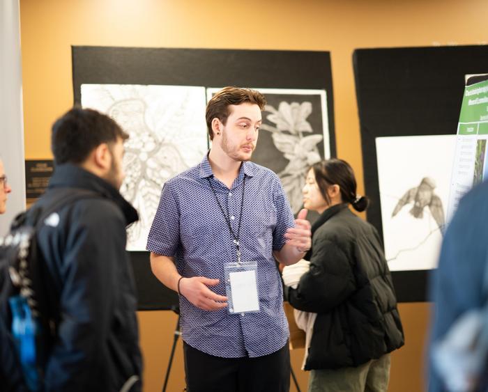 a student in front of a piece of art explaining it to an audience