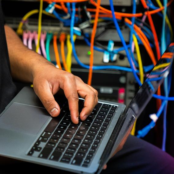 student working on laptop with wires in background