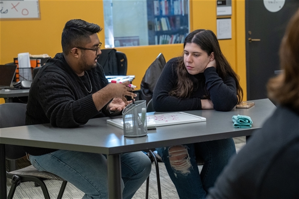 Tutor talking with student at desk