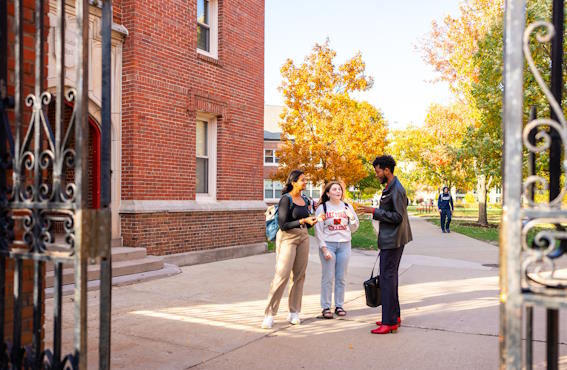 students talking in a group outside amongst dorms on middle campus