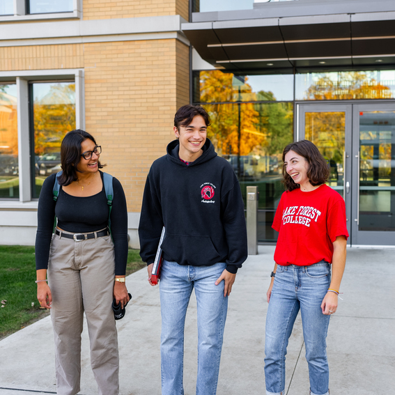 three students in front of the library on campus