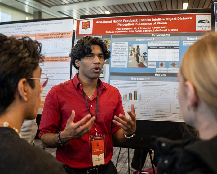 a student presenting in front of a research poster