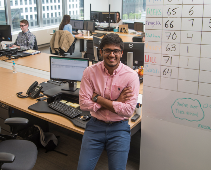 a student smiling in front of a whiteboard in an office