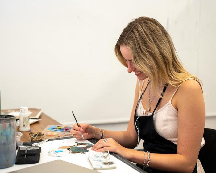 a student painting at a table