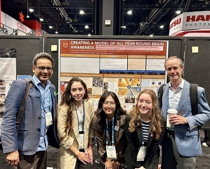 three students and two professors in front of research posterc