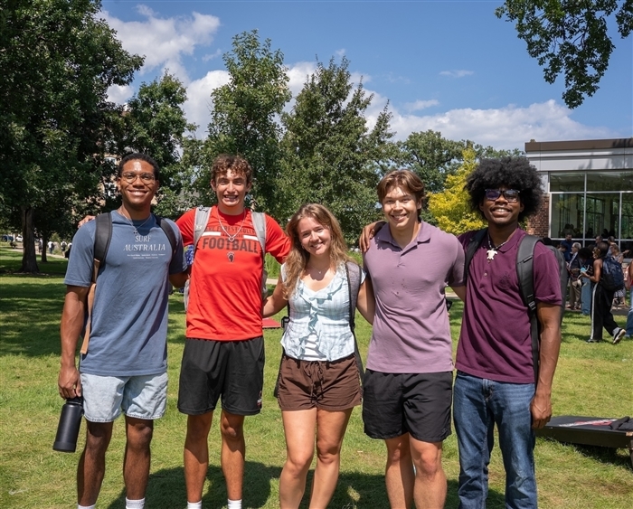 five students arm in arm on campus quad