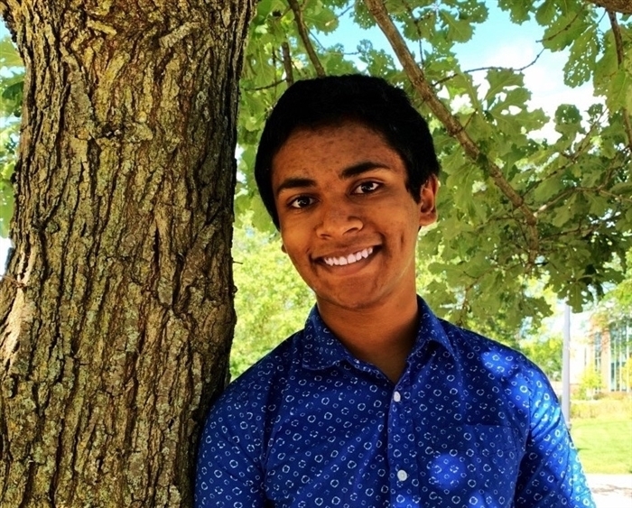 Student leaning against tree on Middle Campus
