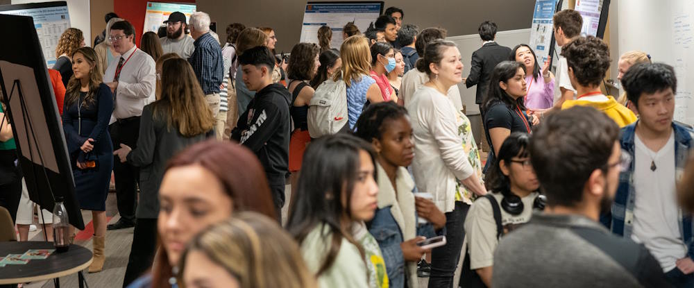 students, faculty, and staff viewing posters at symposium