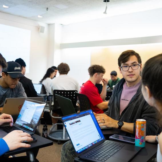 students working on laptops and discussing in a classroom
