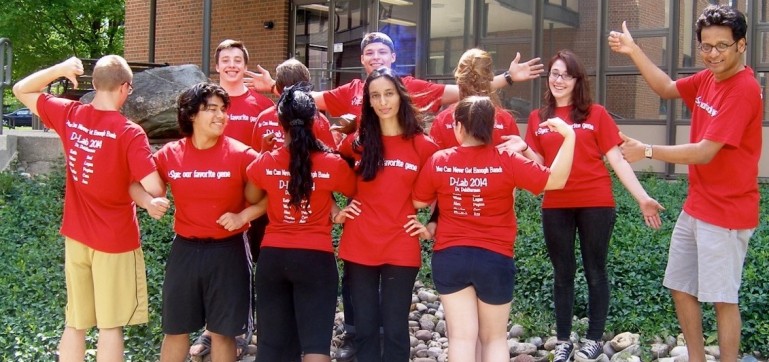 students wearing red T-shirts interlocking arms in front of building
