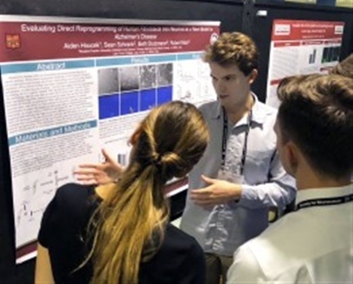 student presenting research poster at conference